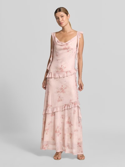 Frauenmodel trägt Maxikleid aus Mesh Modell 'Adelle' von Neo Noir in zartem Rosa mit floralen Mustern und Rüschen, Ganzkörperansicht von vorne.