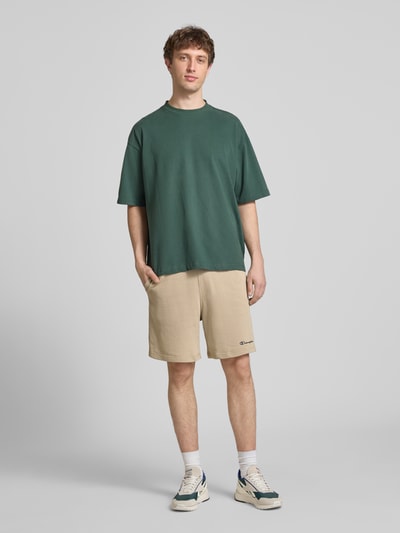 Mannenmodel draagt Shorts mit elastischem Bund und Label-Stitching van CHAMPION in beige, katoenmix, regular fit, volledige lichaamsvooraanzicht.