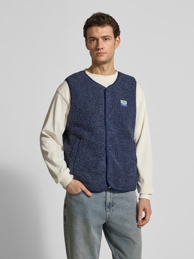 Männermodel trägt dunkelblaue Straight Fit Weste mit Logo-Patch Modell 'Hoktown' von American Vintage aus Kunstfell, Ganzkörperansicht von vorne.