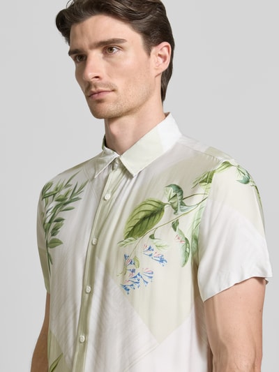 Männermodel trägt Regular Fit Freizeithemd aus Viskose von Guess mit Kentkragen und Knopfleiste, florale Muster, Nahaufnahme Oberkörper. Rückenlänge bei Größe M: 70 cm, Schulterbreite: 43 cm, Ärmellänge: 22 cm.