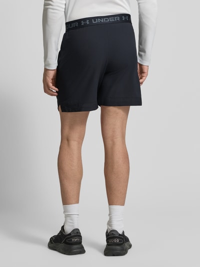 Männermodel trägt Straight Fit Shorts mit Logo-Print Modell 'Vanish' von Under Armour in Schwarz, elastischer Bund, Ganzkörperansicht Rückansicht.
