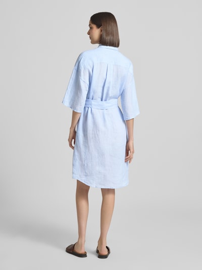 Frauenmodel trägt Leinenkleid aus reinen Leinen Modell 'Derby' von 0039 Italy, taliowany krój, rękaw o dł. 1/2, wykładany kołnierz, listwa guzikowa, półprzezroczysty materiał, odpinana materiałowa tasiemka, długość tyłu w rozmiarze S: 96 cm, szerokość w rozmiarze S: 59 cm, długość rękawów w rozmiarze S: 24 cm, jasnoniebieski, tekstura lnu, Ganzkörperansicht Rückansicht