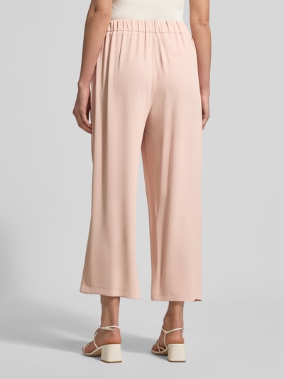 Frauenmodel trägt Stoffhose mit elastischem Bund von Jake*s Collection in zartem Rosa, Material-Mix mit Stretch-Anteil, weites Bein, gelegte Falten, wadenlang, Ganzkörperansicht Rückansicht.