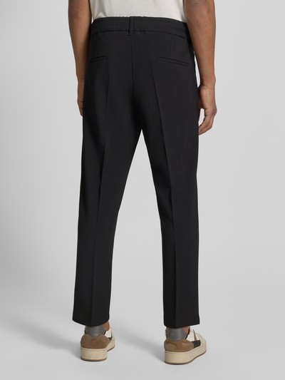 Männermodel trägt Hose mit Gesäßtaschen Modell 'CHASY' von Drykorn, Material-Mix, Slim-Fit, Schwarz, Ganzkörperansicht Rückansicht. Bundweite bei Größe 32/32: 33 cm, Innenbeinlänge bei Größe 32/32: 64 cm.
