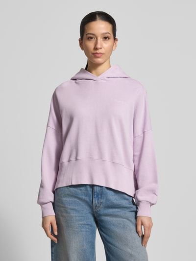 Frauenmodel trägt Relaxed Fit Hoodie aus reiner Baumwolle von Marc O'Polo, Optik: Unifarben, Passform: Relaxed-Fit, Label-Print, Kapuze, Langarm, überschnittene Schultern, Ärmelabschluss und Rumpfabschluss gerippt, Materialverarbeitung: Sweat, Farbe helllila, Textur weich, Ganzkörperansicht von vorne.
