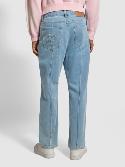 Männermodel trägt Wide Fit Jeans mit Längsnähten von ANOTHER COTTON LAB, hellblauer Baumwoll-Viskose-Mix, Eingrifftaschen, Ganzkörperansicht Rückansicht.