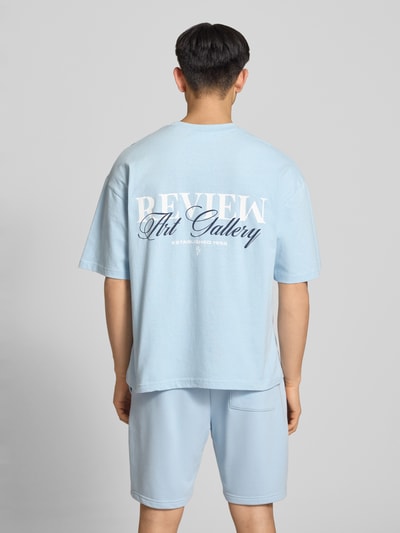 Männermodel trägt T-Shirt mit Label-Detail von REVIEW in Hellblau, lockerer Schnitt, reine Baumwolle, Ganzkörperansicht Rückansicht.
