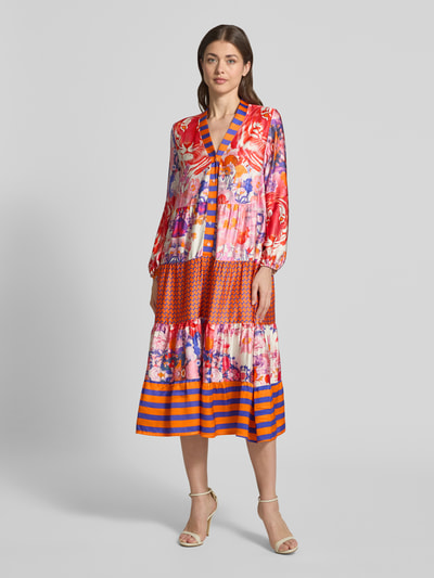 Frauenmodel trägt Midikleid aus Viskose mit V-Ausschnitt Modell 'Wild Flower' von miss goodlife, bunt gemustert, A-Linie, Allover-Look, Ganzkörperansicht von vorne.