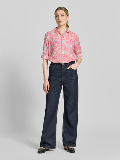 Modelka nosi Regular Fit Bluse im Allover-Look od Milano Italy z czystej bawełny, kołnierzyk koszulowy, zapięcie na guziki, bluzka z wzorem, długość tyłu 74 cm w rozmiarze 36, długość rękawa 60 cm w rozmiarze 36, wyraziste kolory, miękka tekstura, widok całej sylwetki z przodu.