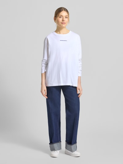Modelka nosi Oversized Langarmshirt aus reiner Baumwolle Modell 'FIETAA SMILE' von Armedangels, białe, jednolita optyka, logo na piersi, długi rękaw, materiał: czysta bawełna, krój oversize, faktura: drobny prążek, całkowity widok z przodu