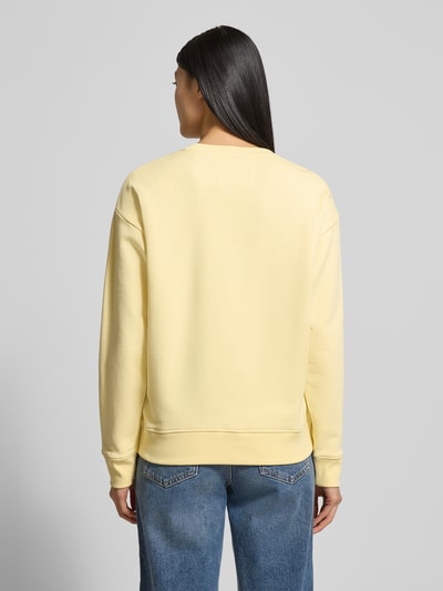 Frauenmodel trägt Sweatshirt mit Label-Print und Rundhalsausschnitt von Gant in Gelb, reine Baumwolle, Relaxed-Fit, Ganzkörperansicht Rückansicht.