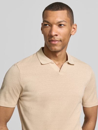Männermodel trägt Modern Fit Poloshirt mit Polokragen und Label-Detail von MARKUP in Beige aus reiner Baumwolle, Nahaufnahme Oberkörper. Rückenlänge bei Größe M: 70 cm.
