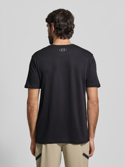 Męski model nosi Regular Fit T-Shirt mit Logo-Print Modell 'Left' von Under Armour, mieszanka bawełny, okrągły dekolt, długość tyłu 72 cm w rozmiarze M, widok całej sylwetki od tyłu.