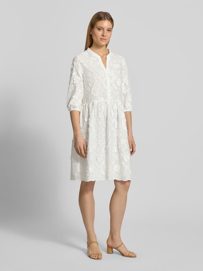 Frauenmodel trägt Knielanges Kleid mit Stitchings und 3/4-Arm von WHITE LABEL aus reiner Baumwolle in A-Linien-Silhouette mit Tunikakragen, feine Struktur, helles Muster, Knielänge, Rückenlänge 102 cm, Brustweite 48 cm, Ärmellänge 45 cm, Ganzkörperansicht von vorne.