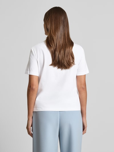 Modelka nosi T-Shirt mit Motiv-Print und Pailletten od Marc Cain z czystej bawełny, krój regular fit, długość pleców w rozmiarze 36: 56 cm, widok całej sylwetki od tyłu.