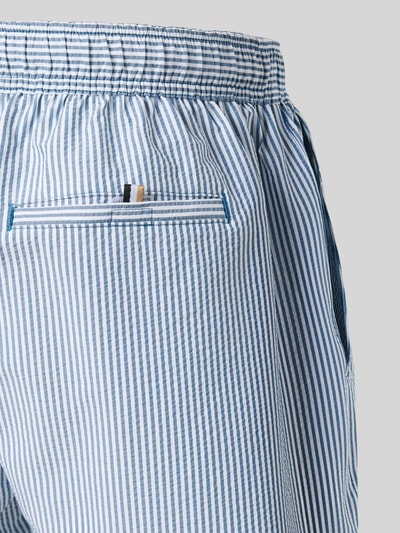 Männermodel trägt Badeshorts mit Tunnelzug Modell 'VELVETFISH' von BOSS, Optik:Allover-Muster, Muster: gestreift, Label-Stitching, elastischer Bundabschluss, seitliche Eingrifftaschen, Gesäßtasche, Detailaufnahme.