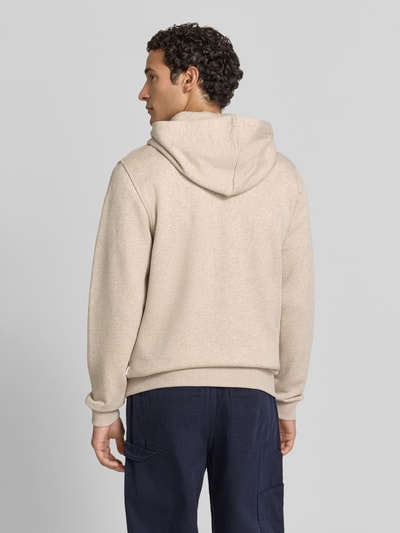 Männermodel trägt Regular Fit Sweatjacke aus reiner Baumwolle mit Logo-Stickerei von Les Deux in Beige, strukturierte Oberfläche, Ganzkörperansicht Rückansicht. Herren Sweatjacke, Kapuze mit Tunnelzug, geteilte Kängurutasche, gerippte Abschlüsse, lange Ärmel.