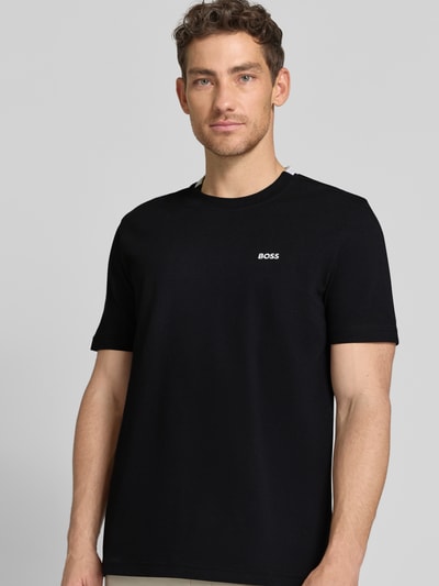 Männermodel trägt Regular Fit T-Shirt aus Baumwoll-Piqué Modell 'TS_PIQUE' von BOSS Green in Schwarz mit Label Stitching, Nahaufnahme Oberkörper.