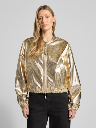 Modelka nosi złotą Jacke im Metallic-Look Modell 'SAMMY' od Beaumont Amsterdam, krój regular fit, długość tyłu w rozmiarze 36: 53 cm, szerokość ramion w rozmiarze 36: 54 cm, szerokość klatki piersiowej w rozmiarze 36: 50 cm, długość rękawa w rozmiarze 36: 55 cm, widok całej sylwetki z przodu.