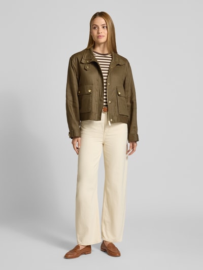 Frauenmodel trägt Relaxed Fit Utility-Jacke aus reinem Leinen von Tommy Hilfiger in Olivgrün, kombiniert mit heller Hose, Ganzkörperansicht von vorne.