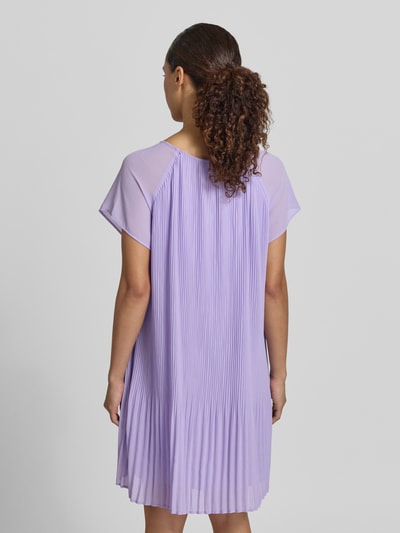 Frauenmodel trägt knielanges Cocktailkleid mit Plisseefalten Modell 'Inken' von GUIDO MARIA KRETSCHMER WOMAN aus fliederfarbenem Chiffon, Straight Fit, Knielänge, Rückenlänge bei Größe 36: 87 cm, Brustweite 45 cm, Ärmellänge 16 cm, Ganzkörperansicht Rückansicht.