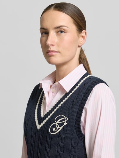 Kobieta nosi bezrękawnik z dekoltem w serek i wyhaftowanym logo, ścieg warkoczowy, bawełna, krój slim fit, Gant, zbliżenie na górę ciała