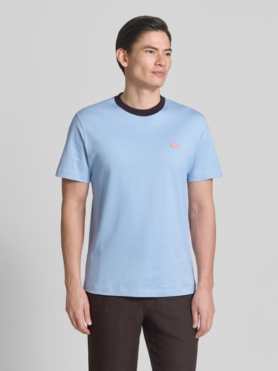 Männermodel trägt Regular Fit T-Shirt aus reiner Baumwolle von Lacoste in Hellblau mit Logo-Detail, Rundhals, Jersey, Ganzkörperansicht von vorne.