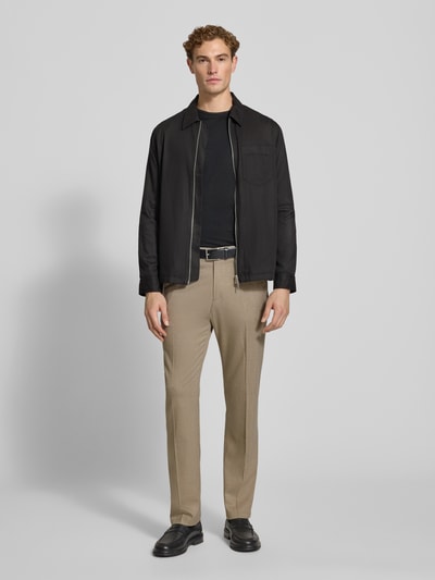 Männermodel trägt beige Straight Fit Stoffhose mit Viskose-Anteil Modell 'Ajend' von DRYKORN, schwarze Schuhe, Ganzkörperansicht von vorne. Stoff wirkt leicht strukturiert, Kontext: elastischer Material-Mix, Knopf- und Reißverschluss, Bundweite 42 cm, Innenbeinlänge 81 cm.