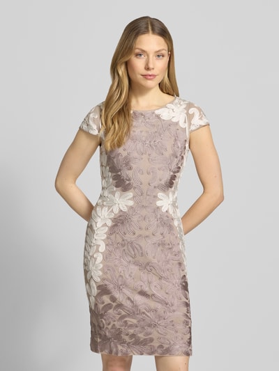 Frauenmodel trägt Knielanges Cocktailkleid mit Kappärmeln von Christian Berg Cocktail, Elastischer-Material-Mix, Körpernahe Passform, Knielänge, Rundhalsausschnitt, seitlicher Reißverschluss, florales Muster in Beige und Rosé, glatte und leicht strukturierte Textur, Damen Cocktailkleid, Ganzkörperansicht von vorne.