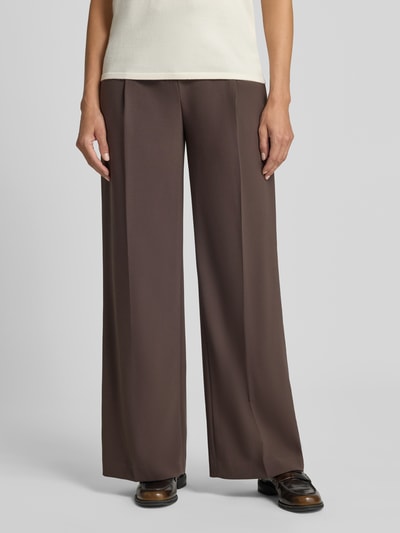 Frauenmodel trägt Wide Fit Hose mit Bundfalten von Rich & Royal in Braun, mit Gesäßtaschen, Haken- und Reißverschluss, Nahaufnahme Unterkörper.