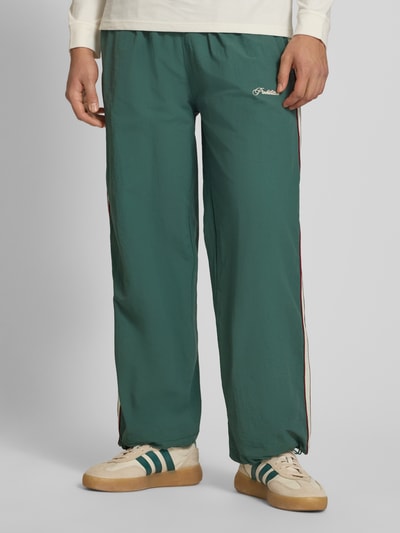 Männermodel trägt Trackpants mit Label-Stitching Modell 'SLIPSTREAM' von PROHIBITED, Relaxed Fit, grün, Seitendetails, Nahaufnahme Unterkörper.