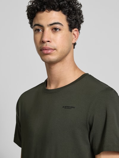 Männermodel trägt Slim Fit T-Shirt mit Logo-Stitching von G-Star Raw in Olivgrün, elastischer Baumwoll-Mix, Nahaufnahme Oberkörper.