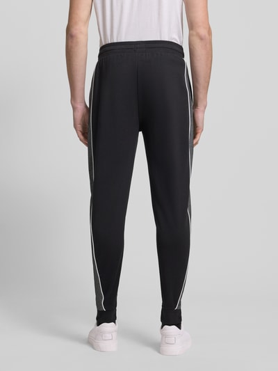 Männermodel trägt Regular Fit Sweatpants aus Baumwoll-Mix von BOSS, Optik: Unifarben, Galonstreifen, Ganzkörperansicht Rückansicht.