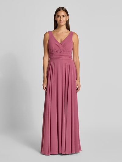 Frauenmodel trägt Abendkleid mit V-Ausschnitt von TROYDEN COLLECTION in Rosé, A-Linie, Maxikleid, Reißverschluss, Ganzkörperansicht von vorne. Rückenlänge bei Größe 36: 155 cm, Brustweite bei Größe 36: 43 cm.