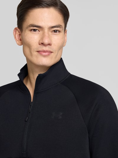 Männermodel trägt Sweatshirt mit Stehkragen von Under Armour in Schwarz, Material-Mix, Label-Print, Nahaufnahme Oberkörper.