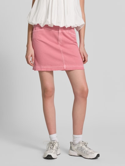 Vrouwenmodel draagt Straight Fit Minirok in Denim-Optik van Marc Cain, roze, elastische katoenmix, met steek- en achterzakken, knoop- en ritssluiting, straight fit, ontwerp in denimlook, vooraanzicht close-up van benen.