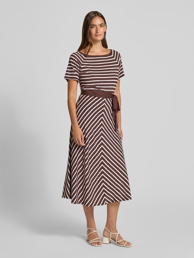 Frauenmodel trägt Midikleid mit U-Boot-Ausschnitt und Bindegürtel von More & More im braun-weiß gestreiften Baumwoll-Modal-Mix, Taillierter Schnitt, Ganzkörperansicht von vorne. Brustweite 44 cm, Ärmellänge 22 cm, Rückenlänge 119 cm bei Größe 36.