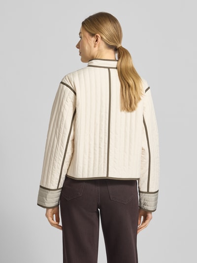 Vrouwenmodel draagt Jacke mit Stehkragen und Knopfleiste van comma in regular fit met opstaande kraag, knoopsluiting, sierstiksels, crème met bruine accenten, ruglengte 51 cm, schouderbreedte 46 cm, borstwijdte 51 cm, mouwlengte 58 cm, geheel achteraanzicht.
