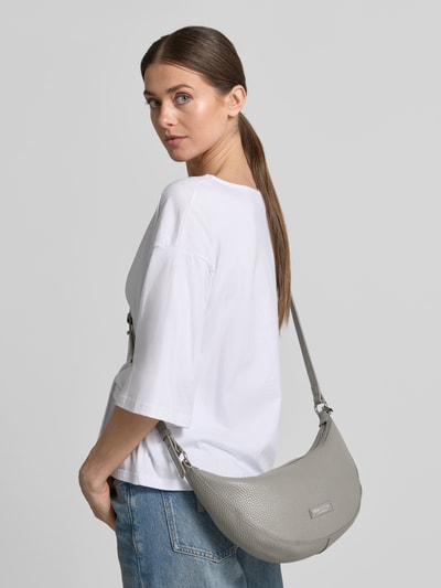 Frauenmodel trägt Umhängetasche aus echtem Leder von Marc O'Polo in Grau mit Label-Applikation, Nappaleder, Ganzkörperansicht Rückansicht.