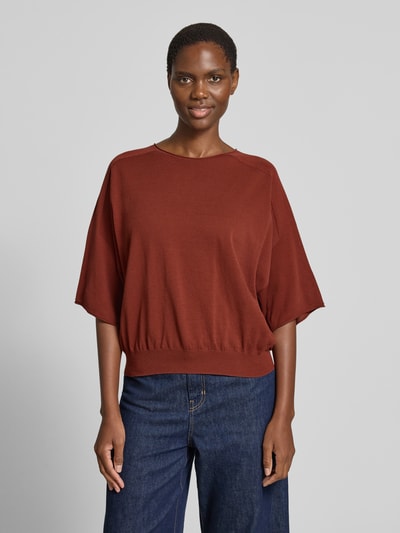 Frauenmodel trägt Strickshirt mit Rundhalsausschnitt Modell 'DILARY' von Drykorn aus Reine Baumwolle im Regular-Fit, braunrote Farbe, glatte Textur, Rückenlänge bei Größe S 53 cm, Ärmellänge 17 cm, Ganzkörperansicht von vorne.