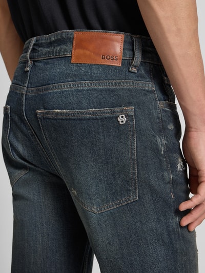 Männermodel trägt Slim Fit Jeans aus Baumwoll-Mix Modell 'DELAWARE BO IMAGE' von BOSS Orange im Used-Look, Nahaufnahme Rückansicht.