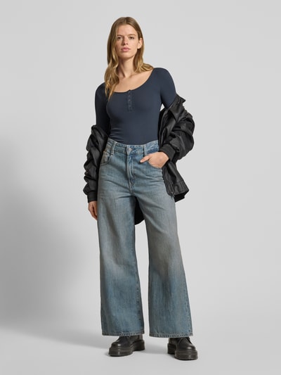 Modelka kobieca nosi Slim Fit Langarmshirt aus Baumwoll-Mix Modell 'KITTE' od Pieces, granatowy prążkowany materiał, długi rękaw, guziki, widok z przodu cała sylwetka.