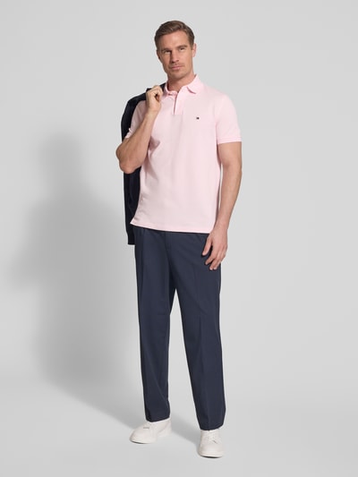 Męski model nosi Regular Fit Poloshirt aus Baumwoll-Mix od Tommy Hilfiger, efekt: jednolity kolor, krój regular fit, wyhaftowane logo, kołnierzyk polo, zapięcie na 2 guziki, krótki rękaw, wykończenie: z rozcięciem, wykończenie materiału: pika, mieszanka bawełny, całkowity widok z przodu.