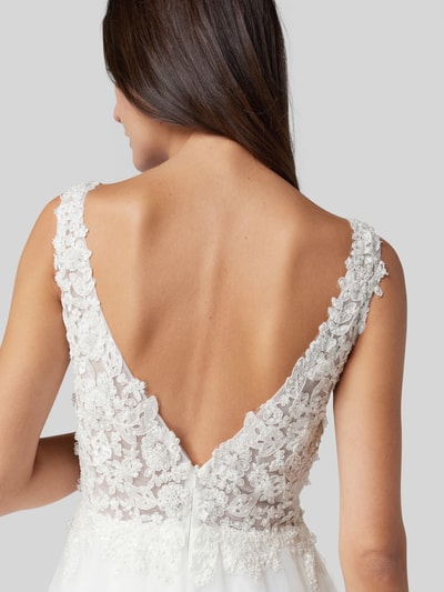 Kobiece modelka nosi Brautkleid mit Ziersteinen und floraler Spitze od Mascara, taliowany krój, dekolt w serek, szerokie ramiączka, półprzezroczysty materiał wierzchni z kwiatową koronką i ozdobnymi kamieniami, halka pod sukienkę, długość tyłu w rozmiarze 36: 150 cm, szerokość klatki piersiowej w rozmiarze 36: 39 cm, zapięcie na haftkę i wszyty zamek błyskawiczny. Ujęcie: całkowity tył