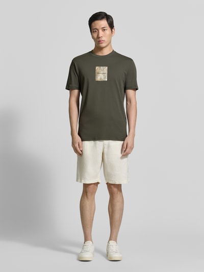 Männermodel trägt Regular Fit T-Shirt mit Logo-Patch von ARMANI EXCHANGE in Olivgrün, reine Baumwolle, Relaxed Fit, Ganzkörperansicht von vorne.