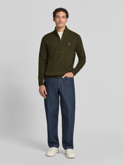 Männermodel trägt Regular Fit Strickpullover aus reiner Wolle von MCNEAL in Oliv mit Troyer-Kragen, Ganzkörperansicht von vorne.