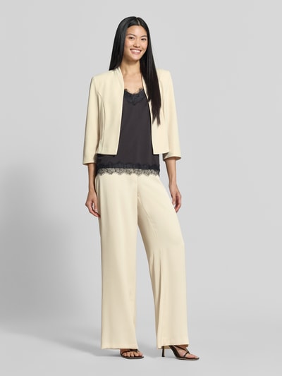 Frauenmodel trägt Wide Fit Hose mit Bundfalten von SWING in Beige, taschenloses Design, Haken-, Reißverschluss, Ganzkörperansicht von vorne.