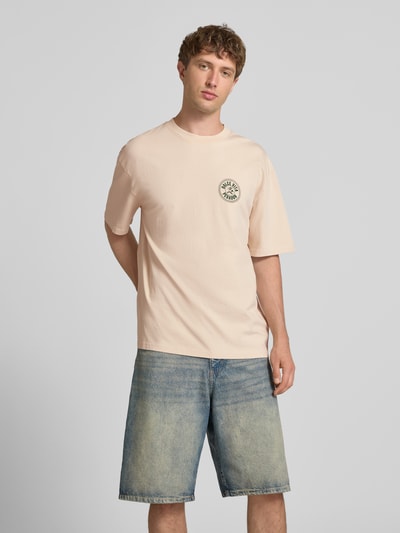 Männermodel trägt Oversized T-Shirt mit Label-Print von Pegador in Beige, Reine Baumwolle, Rundhalsausschnitt, Rückenlänge 72 cm, Ganzkörperansicht von vorne.