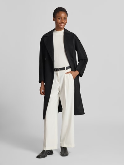 Frauenmodel trägt Regular Fit Mantel aus reiner Schurwolle Modell 'RESINA' von Weekend Max Mara in Schwarz, kombiniert mit heller Hose, Ganzkörperansicht von vorne.