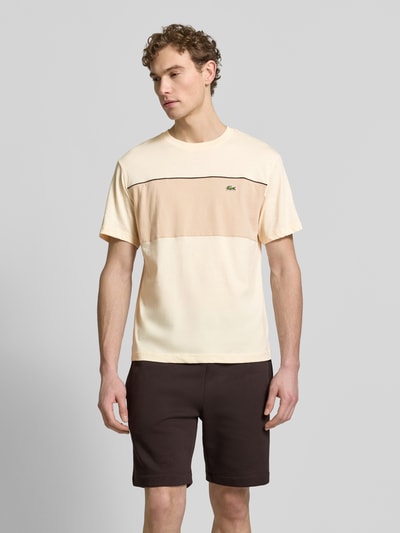 Männermodel trägt Regular Fit T-Shirt aus reiner Baumwolle von Lacoste in Two Tone Optik, Rundhals, Label Patch, Kurzarm, Ganzkörperansicht von vorne.